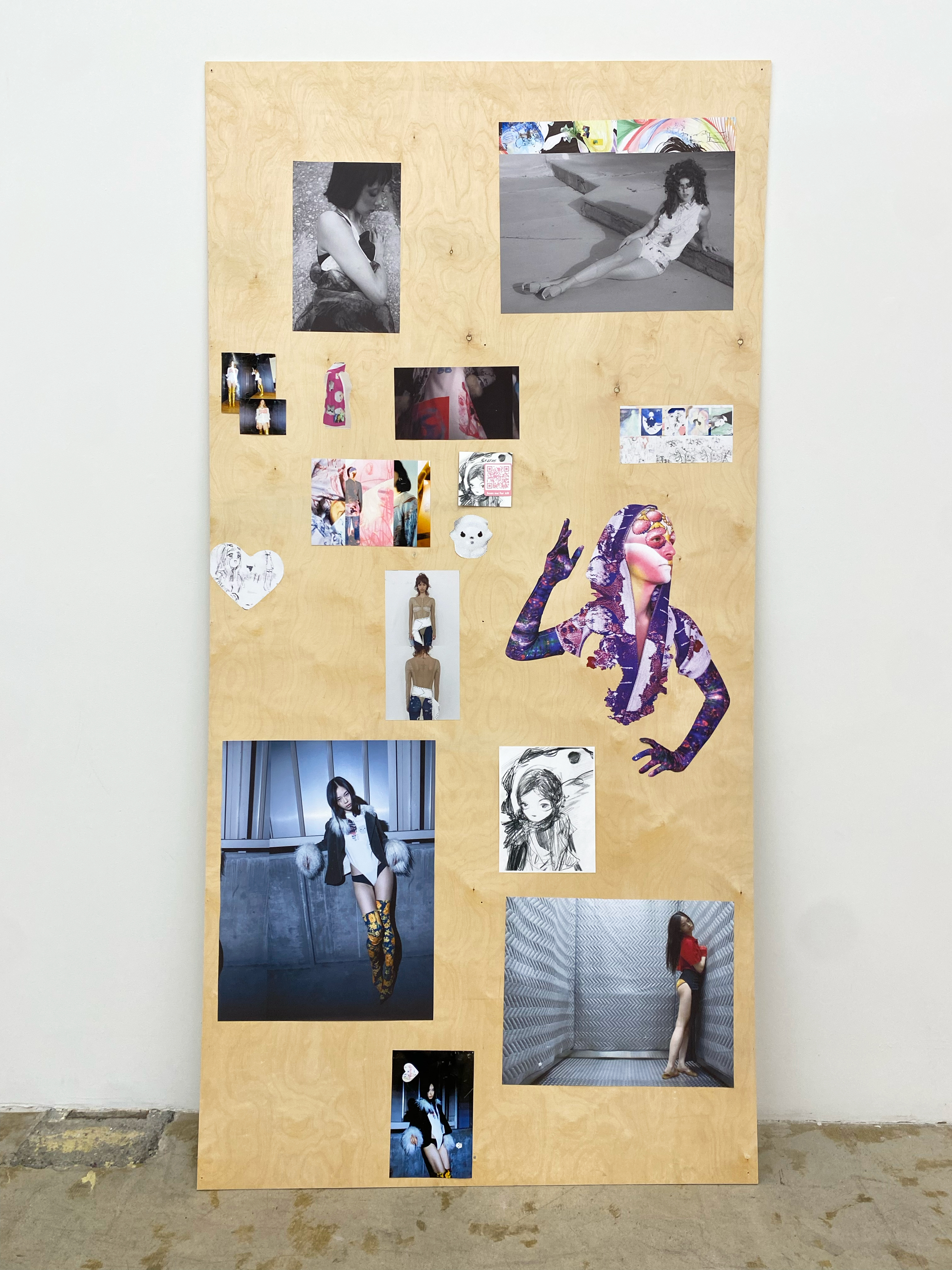Vertial wood board leaning against a wall with collaged images and drawings by Minji Son